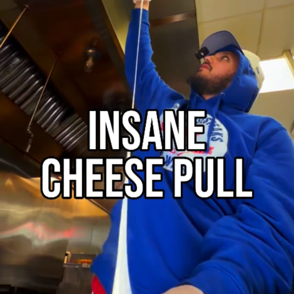 Man in blue hoodie pulling a long string of melted cheese from a Buffalo Eatz dish.